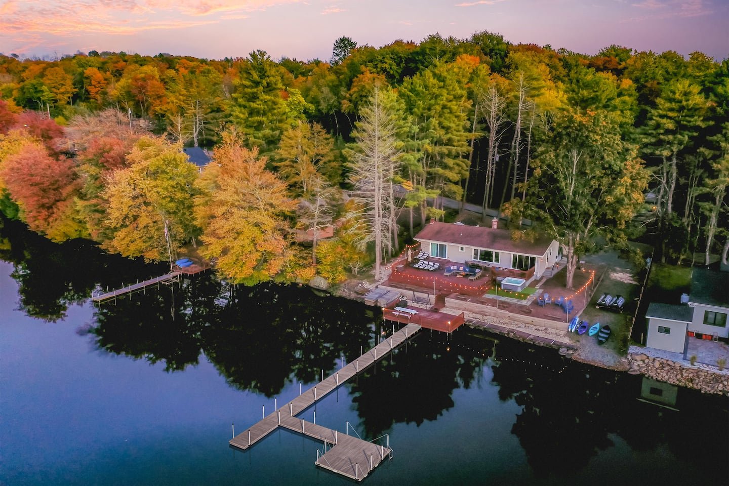 Lakehouse and its decks beside Sackett Lake at dusk, surrounded by autumn trees